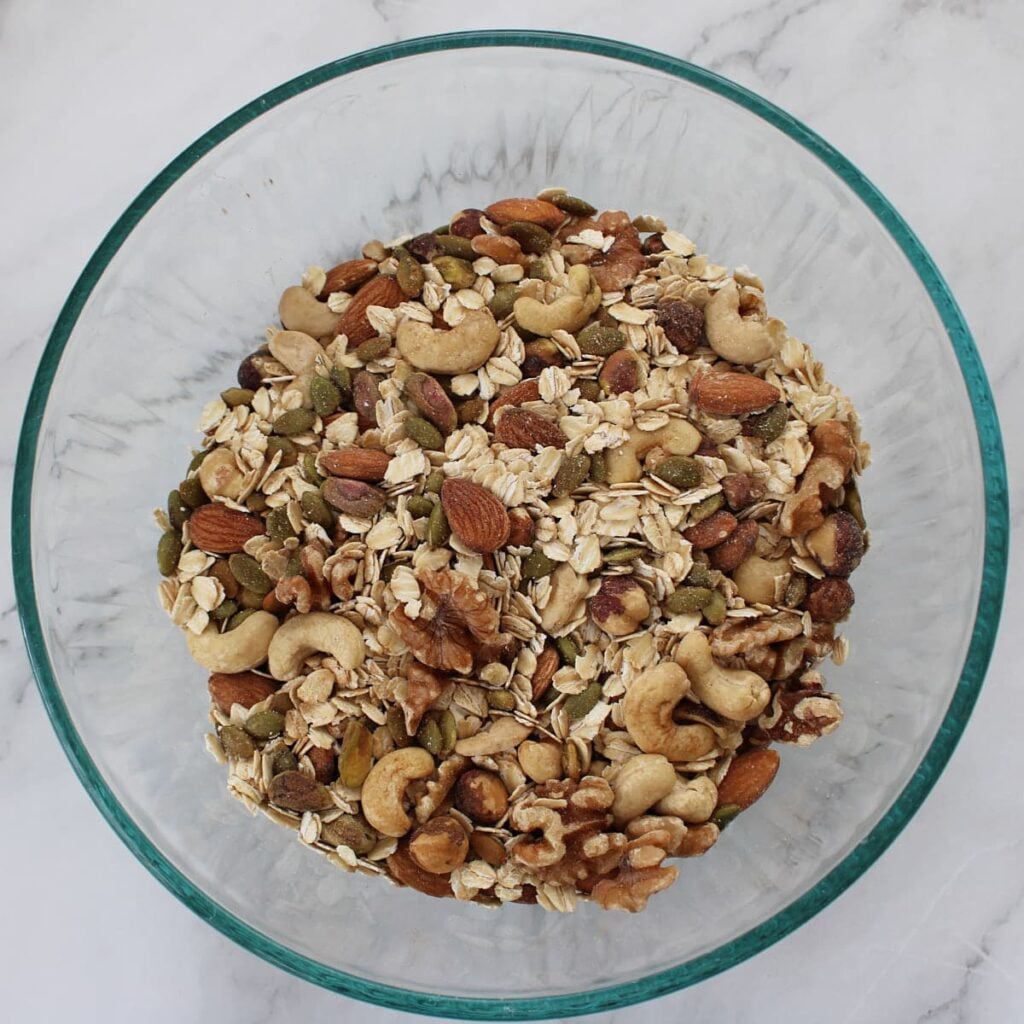 Dry ingredients for sourdough granola mixed together in a clear bowl.