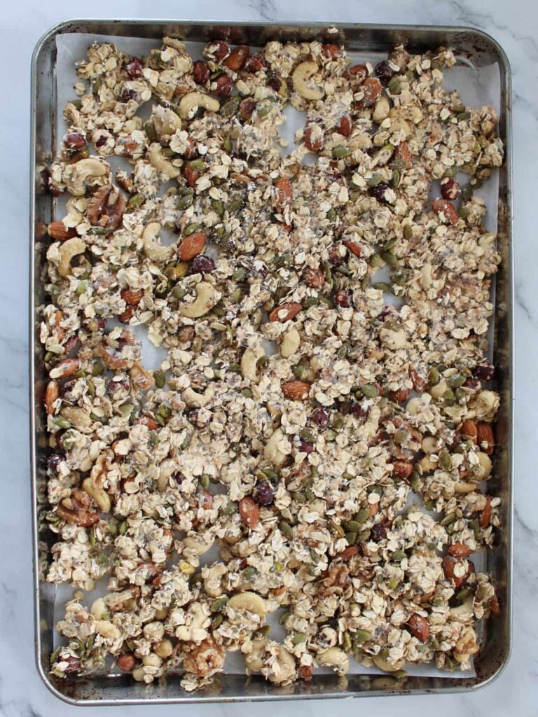 Sourdough granola spread out on a sheet pan before baking.
