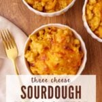 Three bowls of sourdough mac and cheese next to a cream cloth napkin and a gold fork.