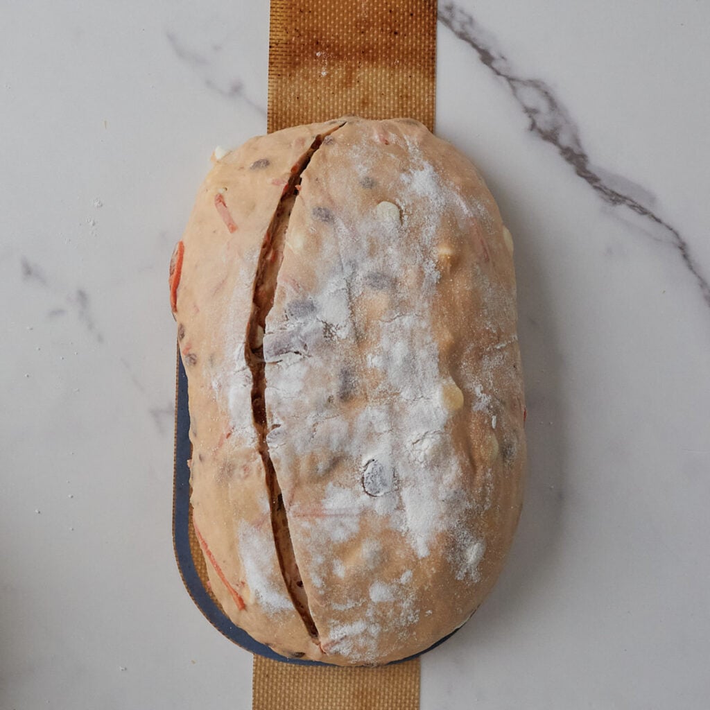 Carrot Cake Sourdough Bread on a bread sling with a score cut into the dough before baking.