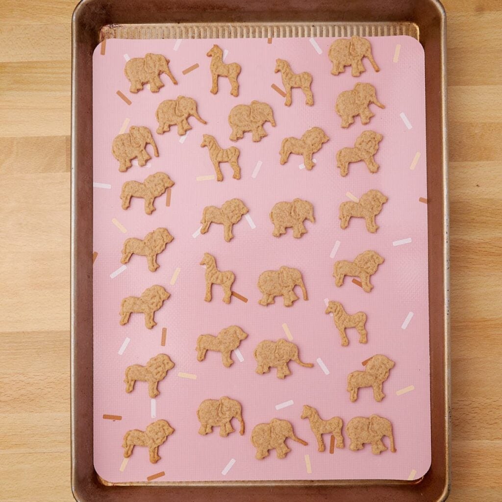 Freshly baked Sourdough Animal Crackers on a sheet pan lined with a silicone baking mat.