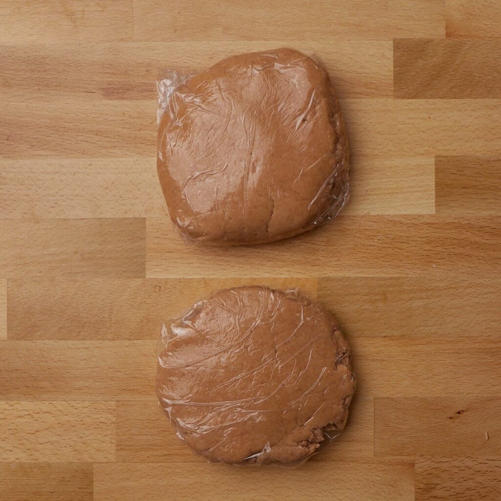 Two dough balls wrapped in plastic wrap to chill for sourdough animal crackers.