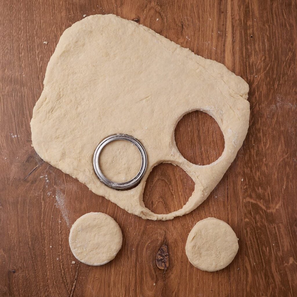 Cutting out biscuits from the dough using a mason jar lid.