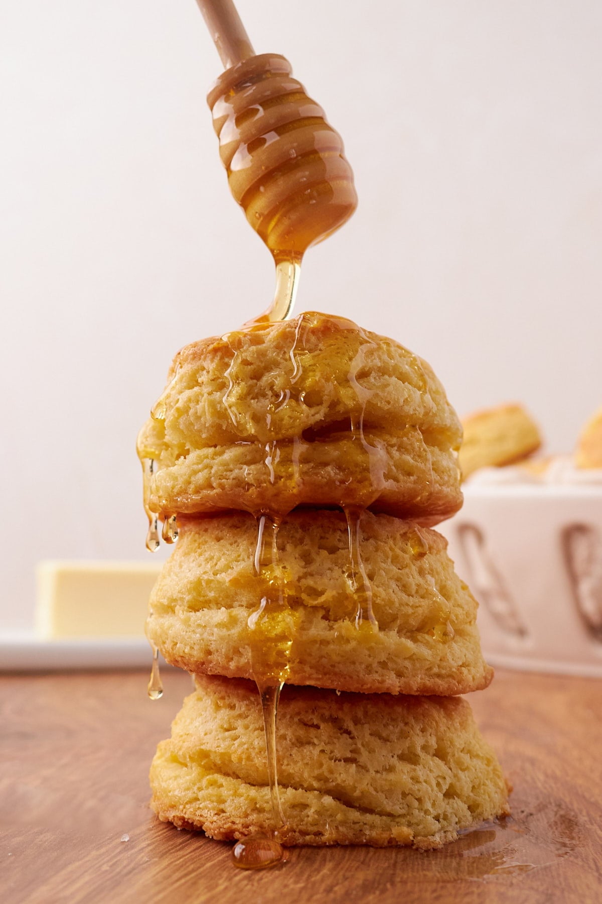 Three sourdough buttermilk biscuits stacked on top of each other with honey being drizzled on top.