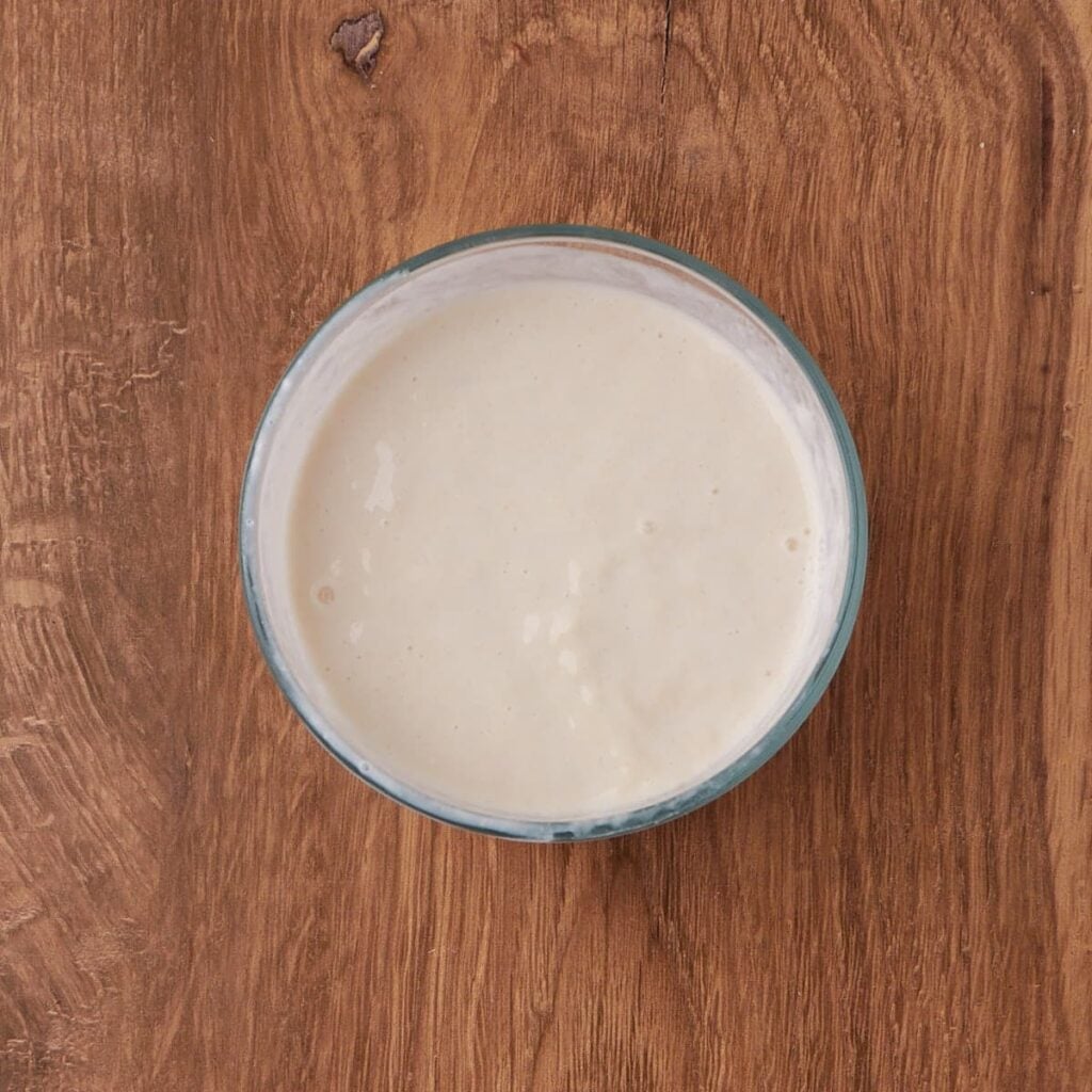 Wet ingredients for sourdough buttermilk biscuits in a clear bowl.