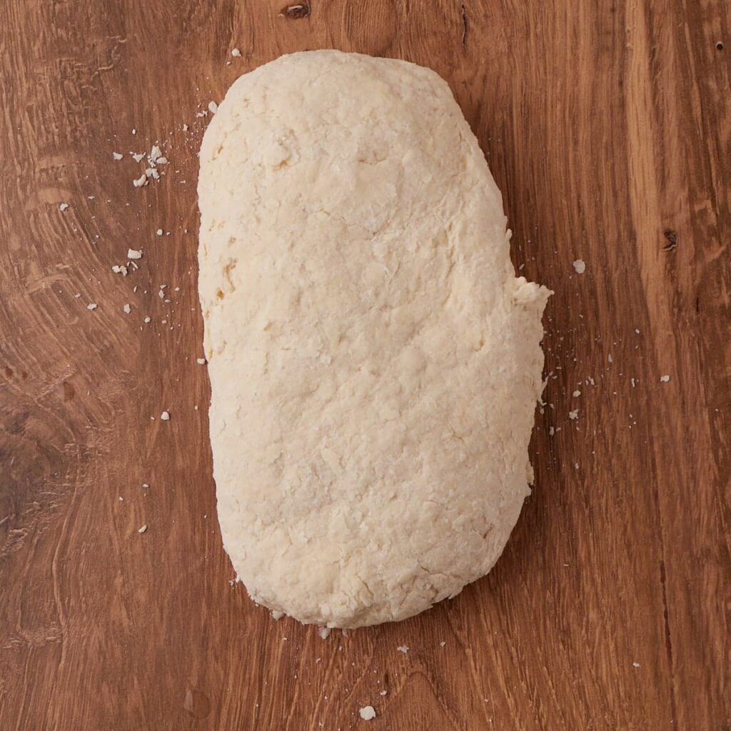 Dough for sourdough buttermilk biscuits on a wooden surface.