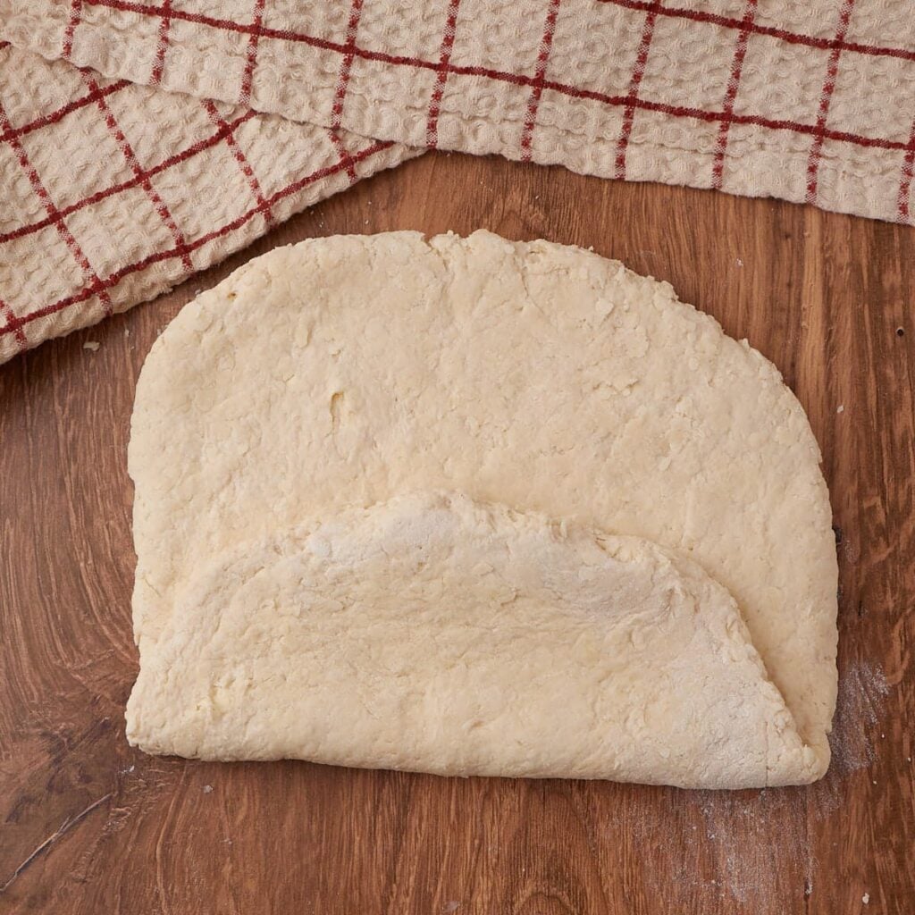 Shaping dough for Sourdough Buttermilk Biscuits on a wooden surface.