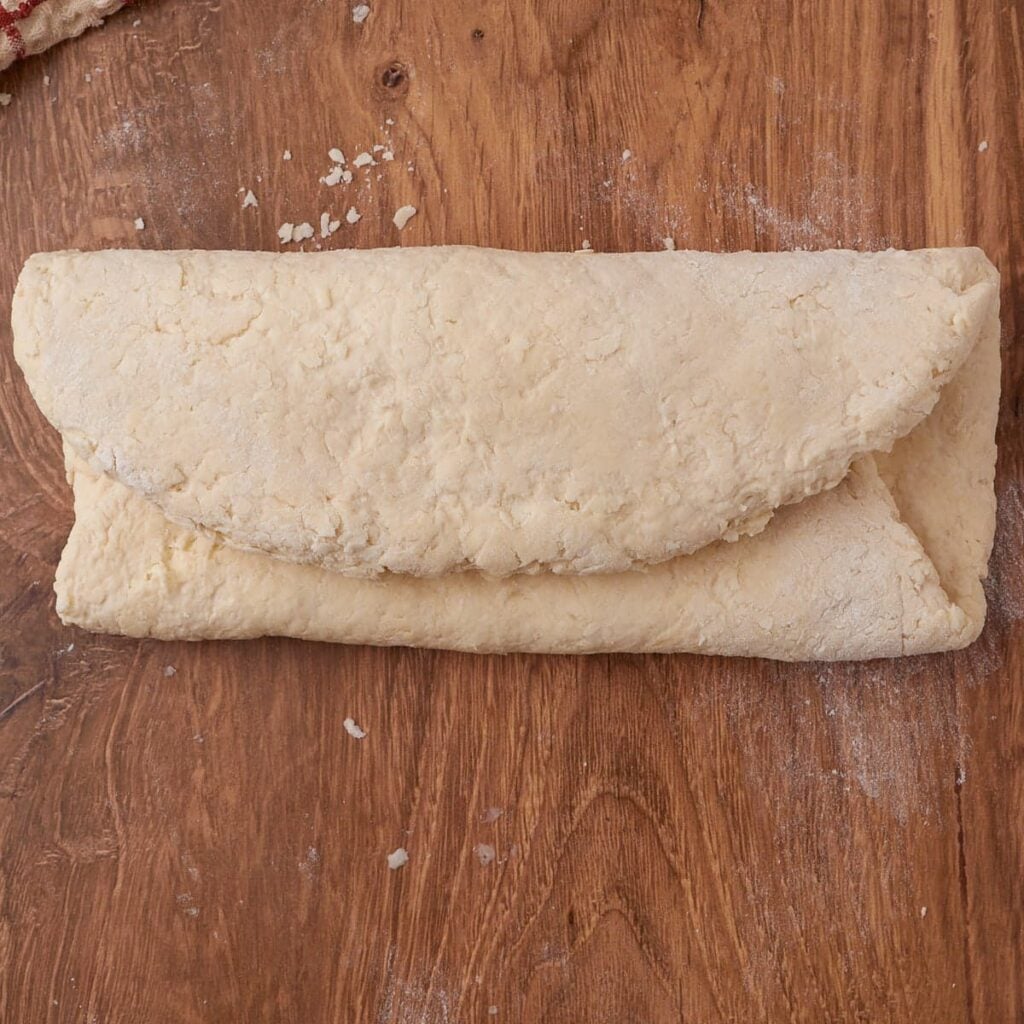Shaping dough for Sourdough Buttermilk Biscuits on a wooden surface.