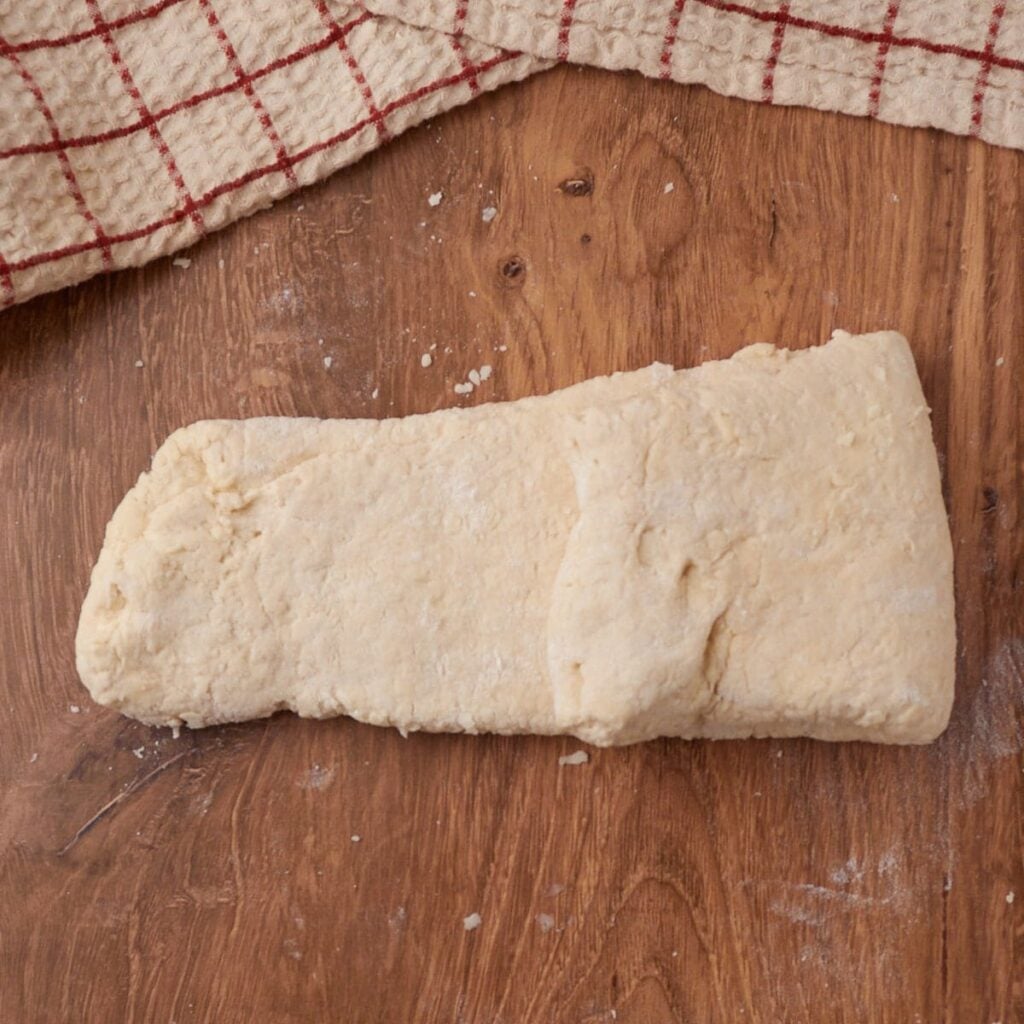Shaping dough for Sourdough Buttermilk Biscuits on a wooden surface.