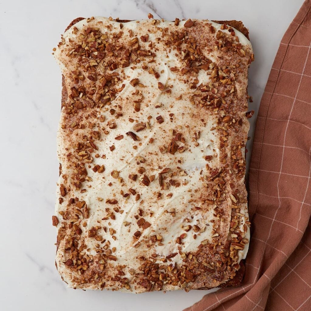 Cream cheese frosting and nut crunch added on top of baked sourdough carrot cake.