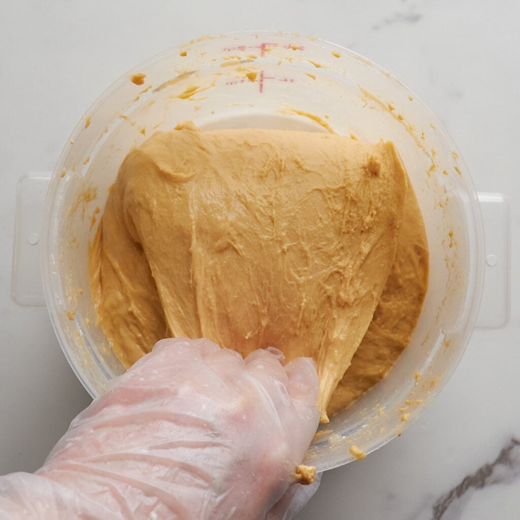 Hand folding dough down during stretch and folds.