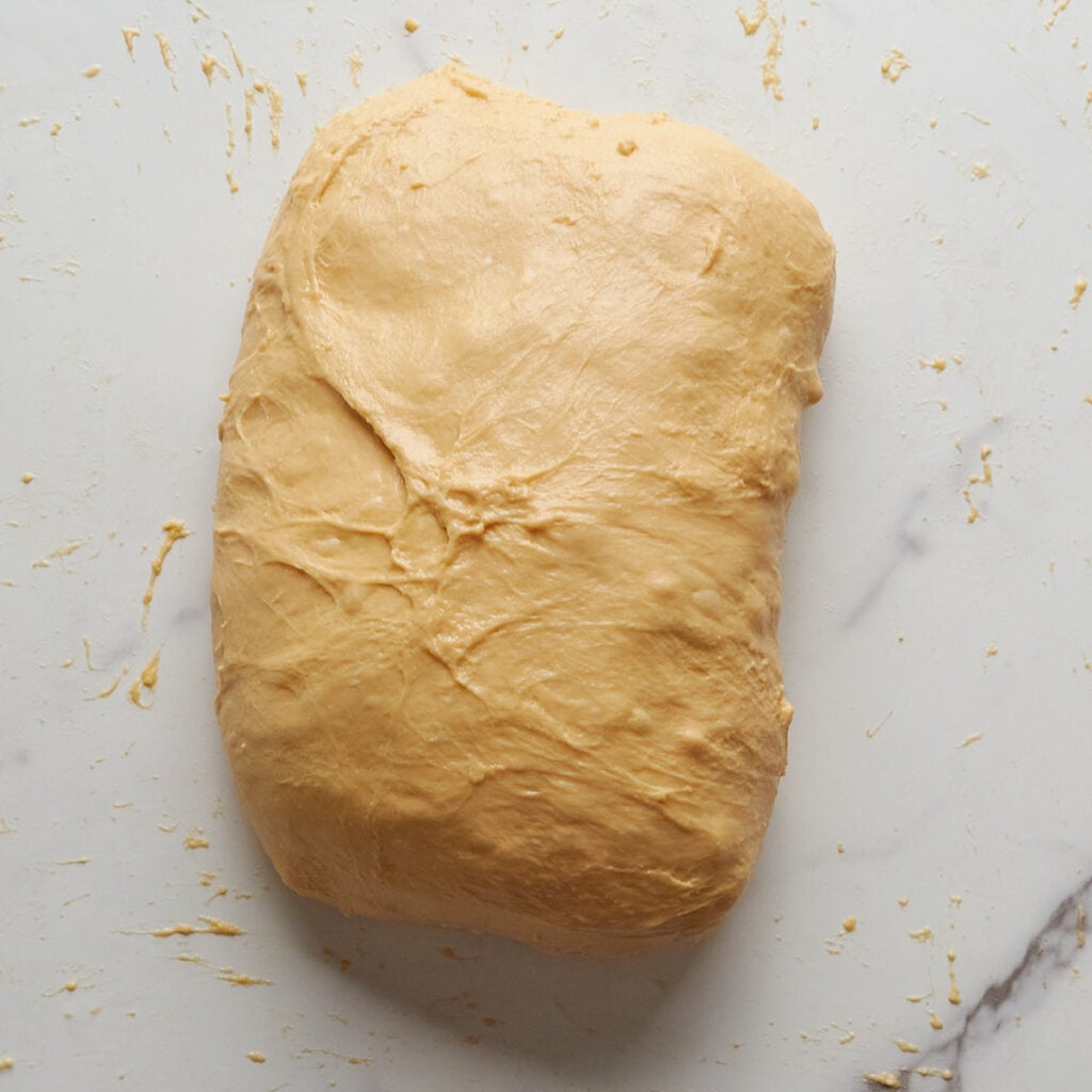 Dough being shaped during lamination for carrot cake sourdough bread.