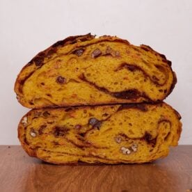 Carrot Cake Sourdough Bread cut in half and stacked on top of each other on a wooden surface.