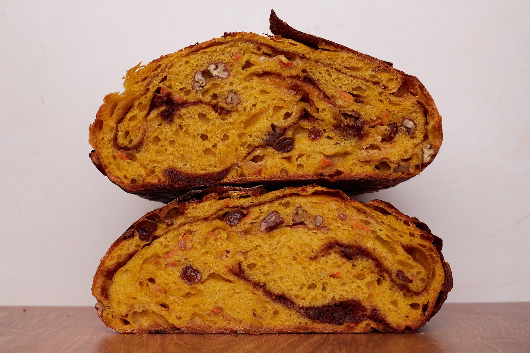 Carrot Cake Sourdough Bread cut in half and stacked on top of each other on a wooden surface.
