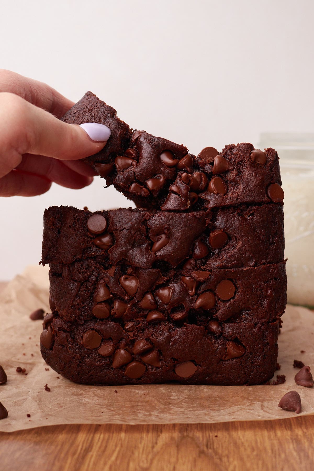 Four slices of Sourdough Chocolate Banana Bread stacked on to of each other with a hand picking up the top slice.
