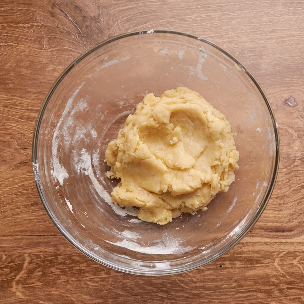 Shortbread dough for sourdough lemon bars mixed in a clear bowl. 
