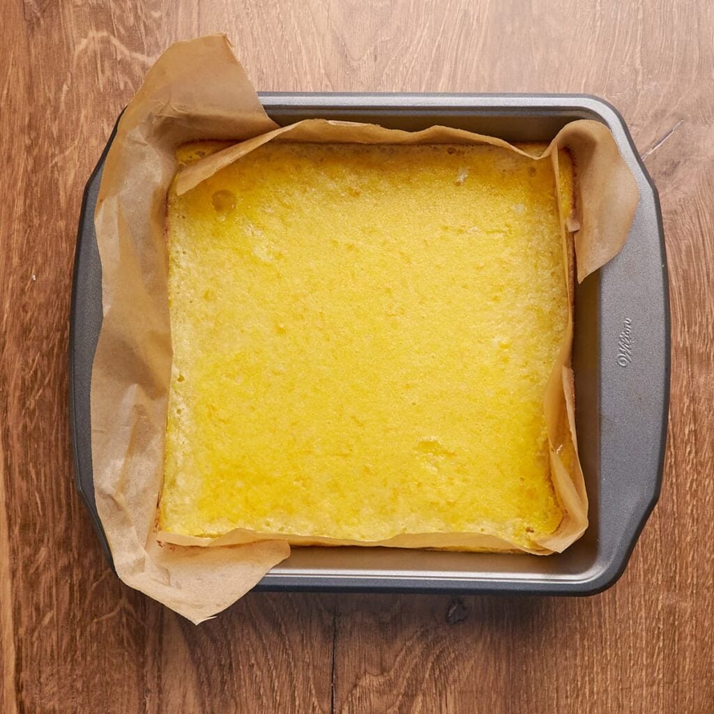 Freshly baked sourdough lemon bars in a 9x9 pan lined with parchment paper.