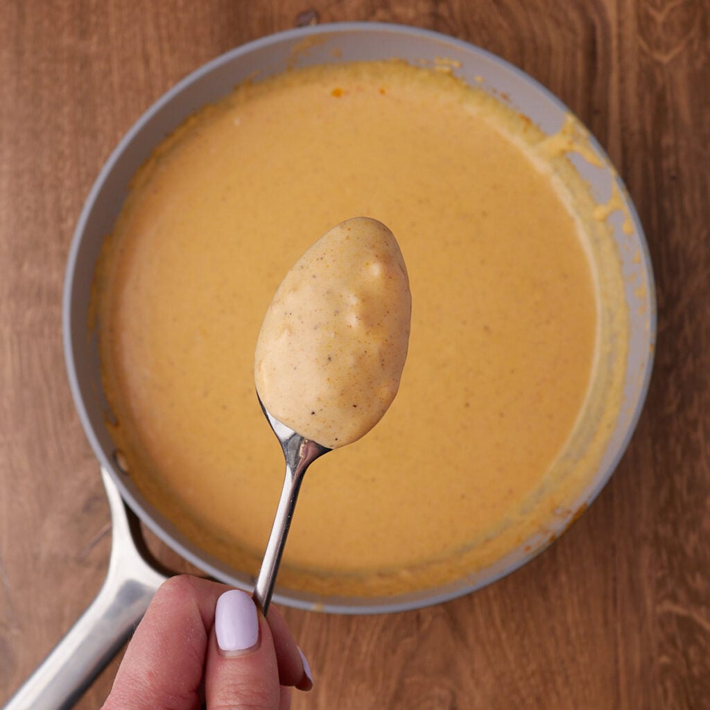 A spoon with cheese sauce on the back of it to see how thick it is.