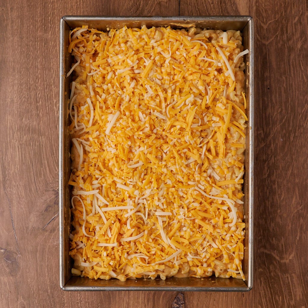 Sourdough mac and cheese in a 9x13 pan with a sprinkle of cheese before baking.