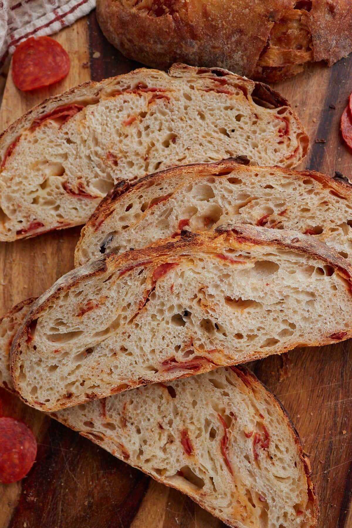 Four slices of pepperoni and mozzarella cheese sourdough bread on a wooden cutting board.