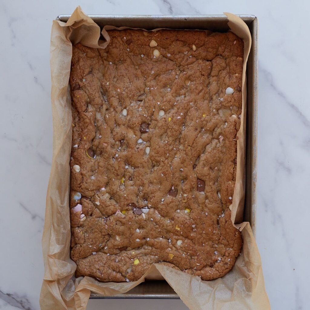 Freshly baked Cadbury Egg Sourdough Cookies bars in a parchment lined 9x13 pan.