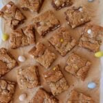 Sliced Cadbury Egg Sourdough Cookie bars on brown parchment paper with Cadbury mini eggs scattered around.