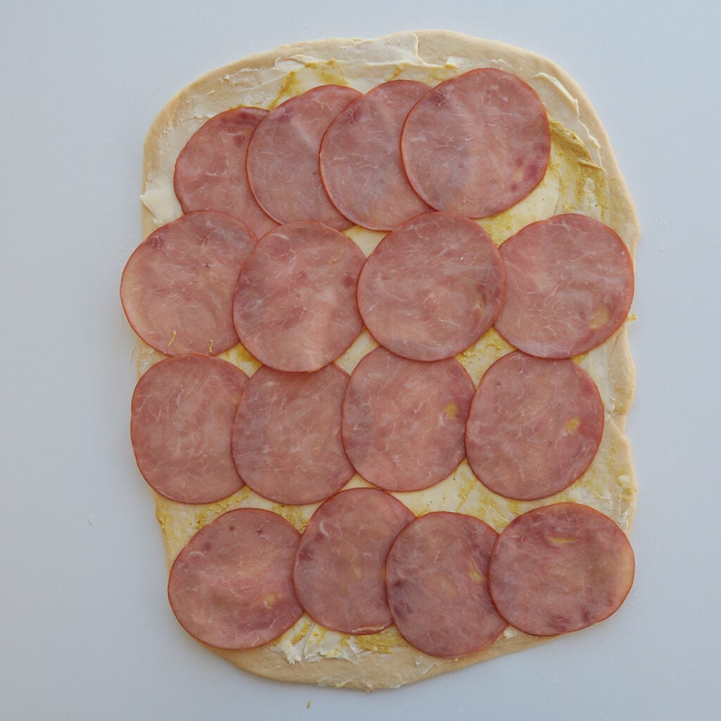 Ham added on top of the dough for Sourdough Ham and Cheese Rolls.