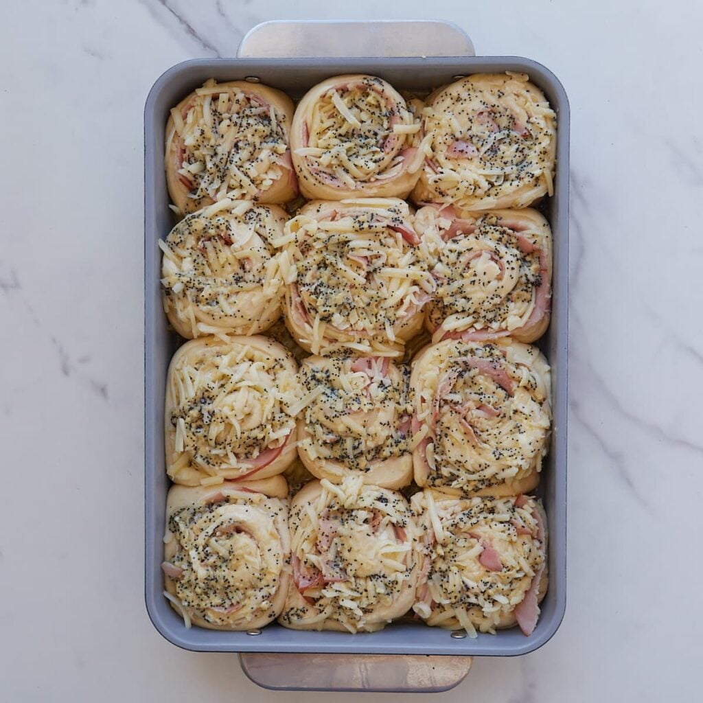 Topping added on top of sourdough ham and cheese rolls in a 9x13 pan.