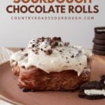 One Cookies and Cream Sourdough Chocolate Roll on a brown plate with oreos next to it.