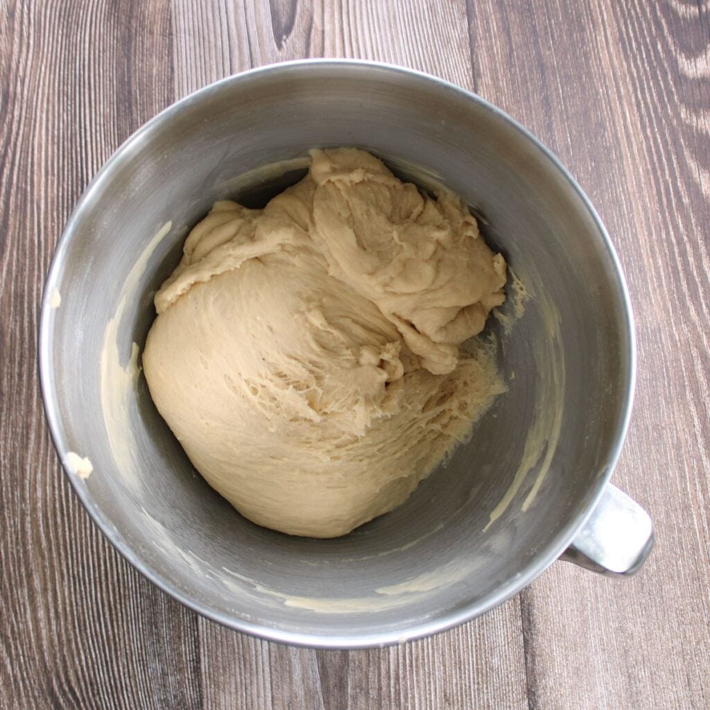 Dough for sourdough discard hot dog buns in the bowl of a stand mixer after kneading.