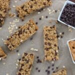 Sourdough granola bars on brown parchment paper with oats and mini chocolate chips scattered around.