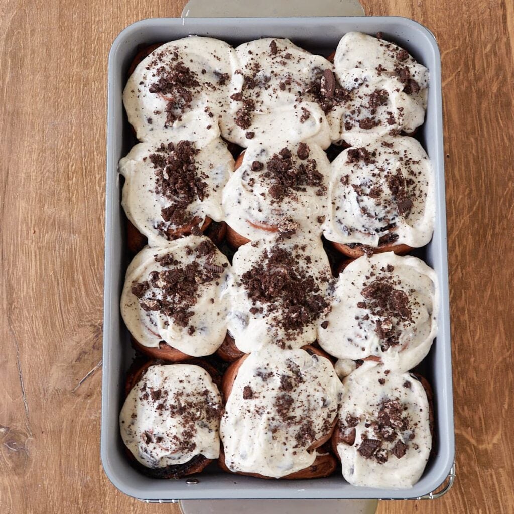 Cookies and Cream Sourdough Chocolate Rolls in a 9x13 pan with cream cheese frosting and crushed oreos on top.