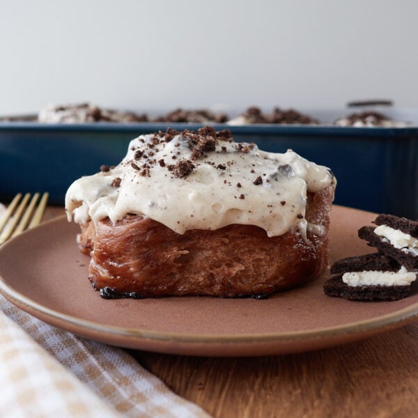 One Cookies and Cream Sourdough Chocolate Roll on a brown plate with oreos next to it.