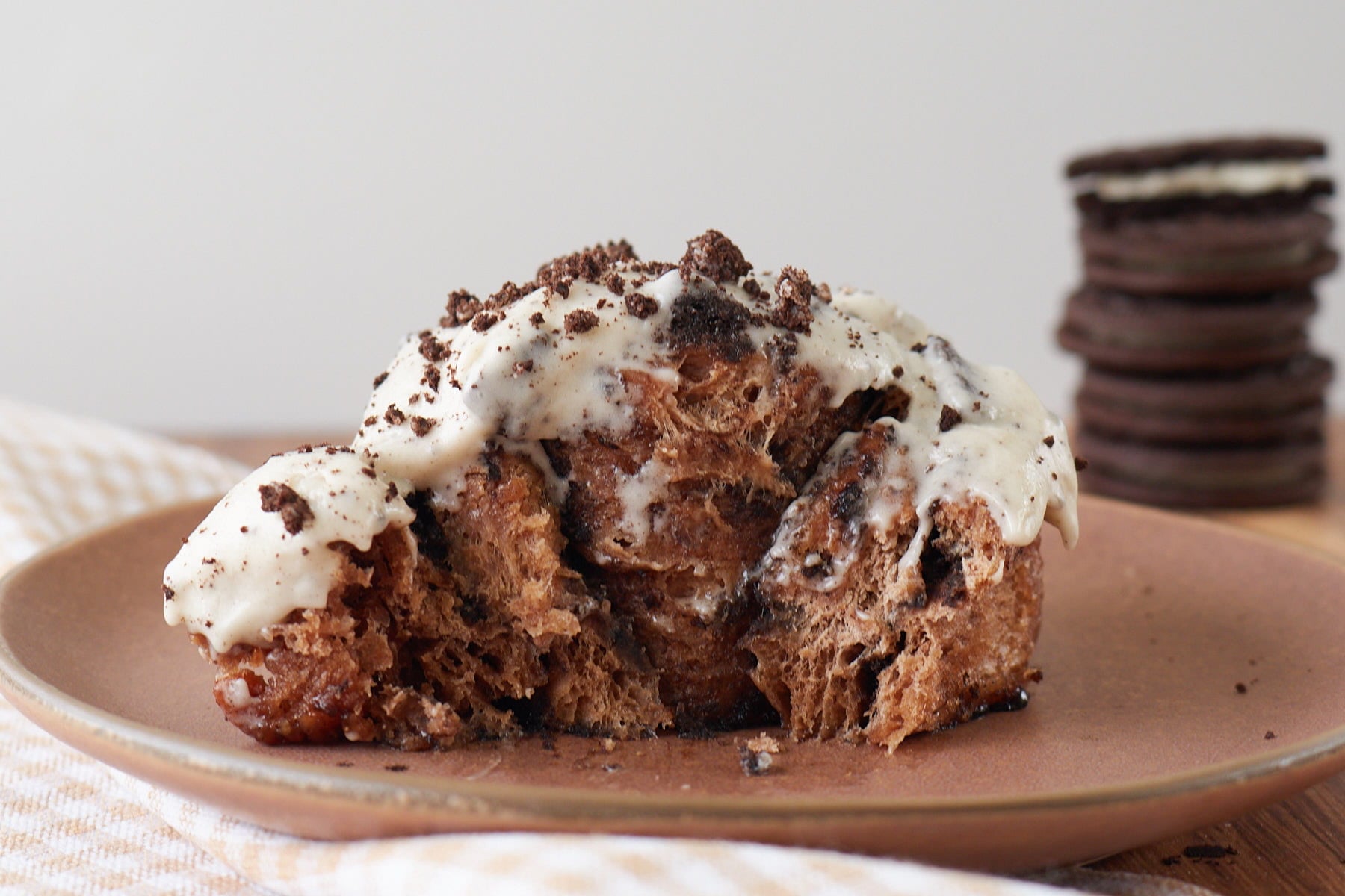 One Cookies and Cream Sourdough Chocolate Roll on a brown plate with a bite taken out of it.