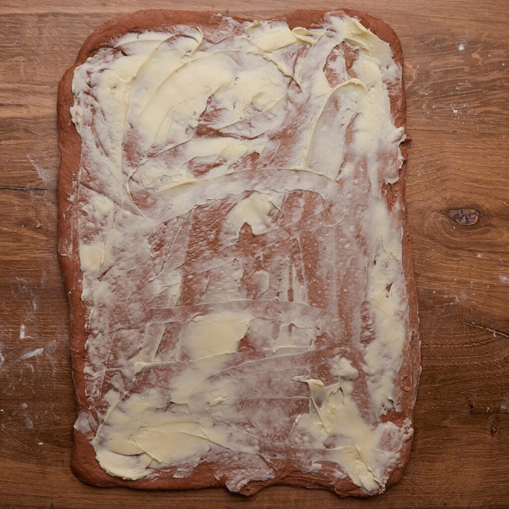 Dough for Cookies and Cream Sourdough Chocolate Rolls rolled into a rectangle with softened butter spread over it.
