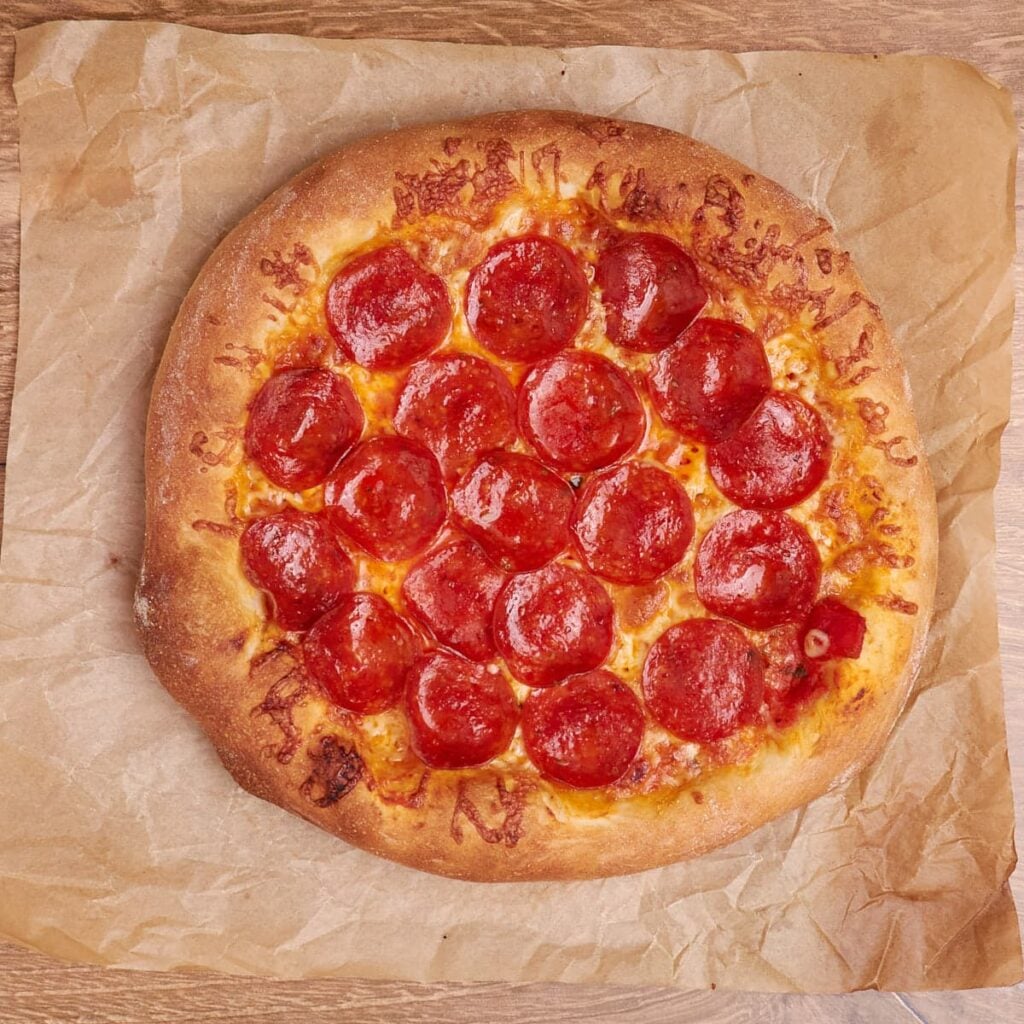 Freshly baked pepperoni pizza made from sourdough discard pizza dough on parchment paper.