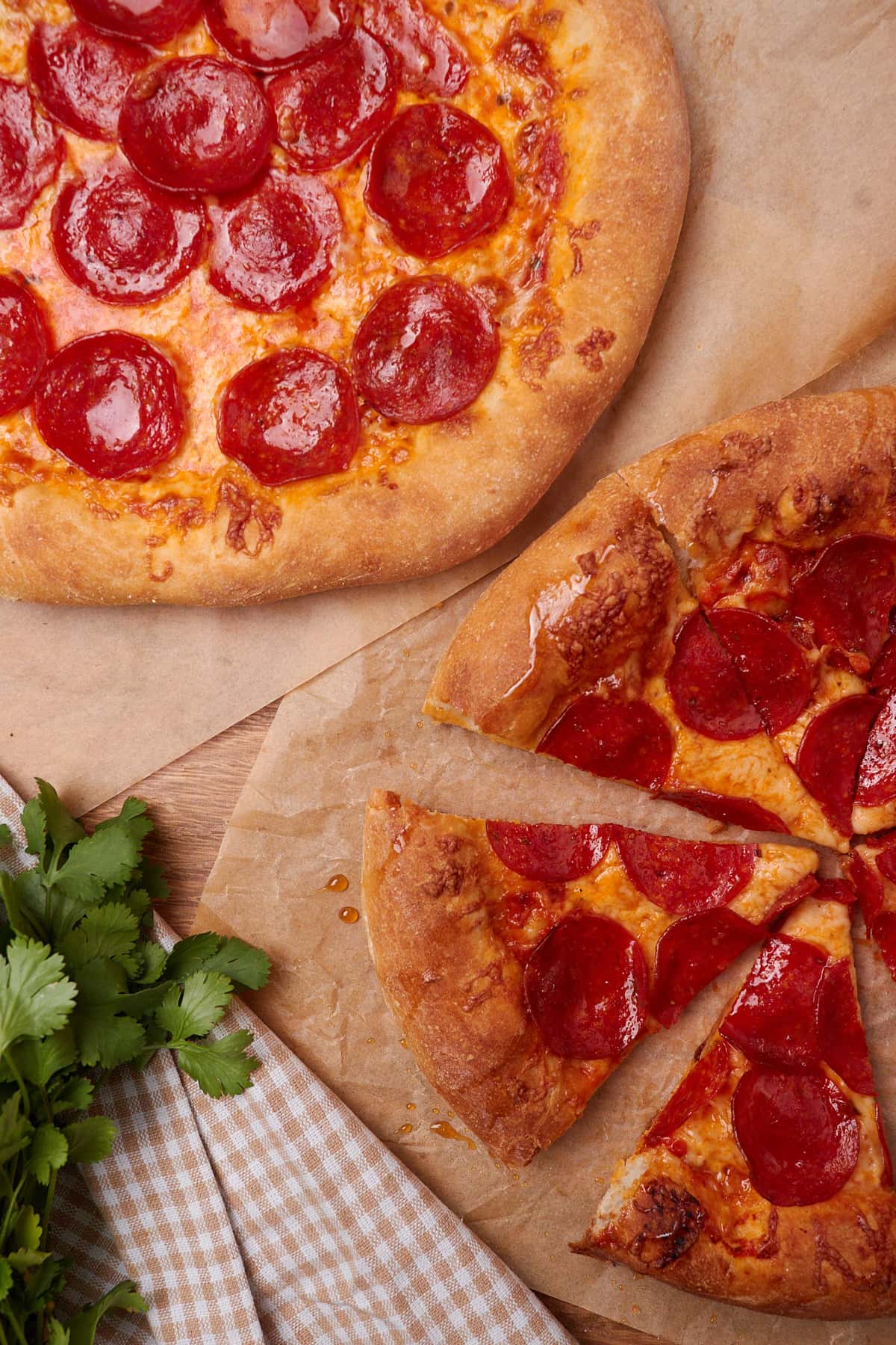 Two pepperoni pizzas made from sourdough discard pizza dough on parchment paper.