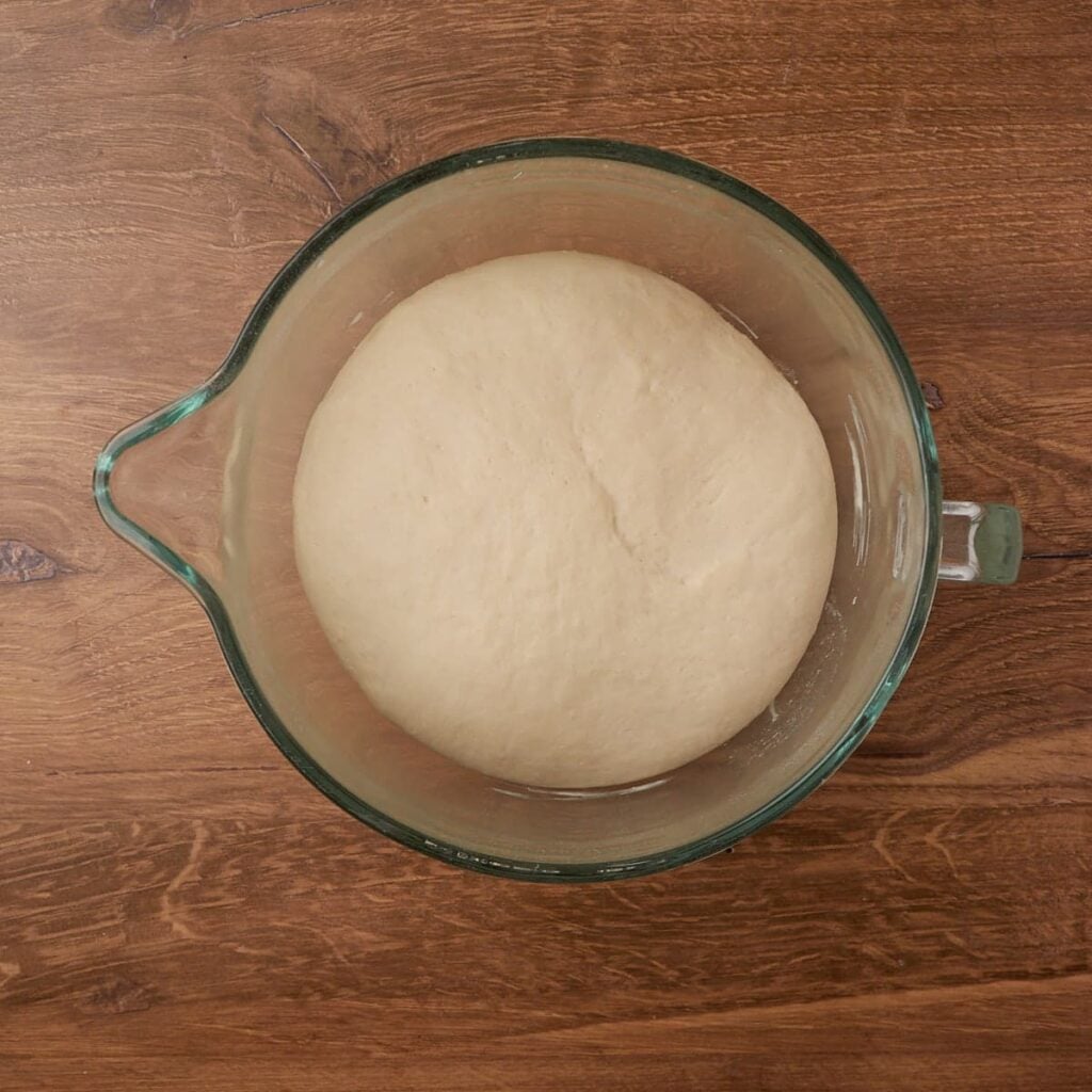 Sourdough discard pizza dough in a clear bowl after rising.