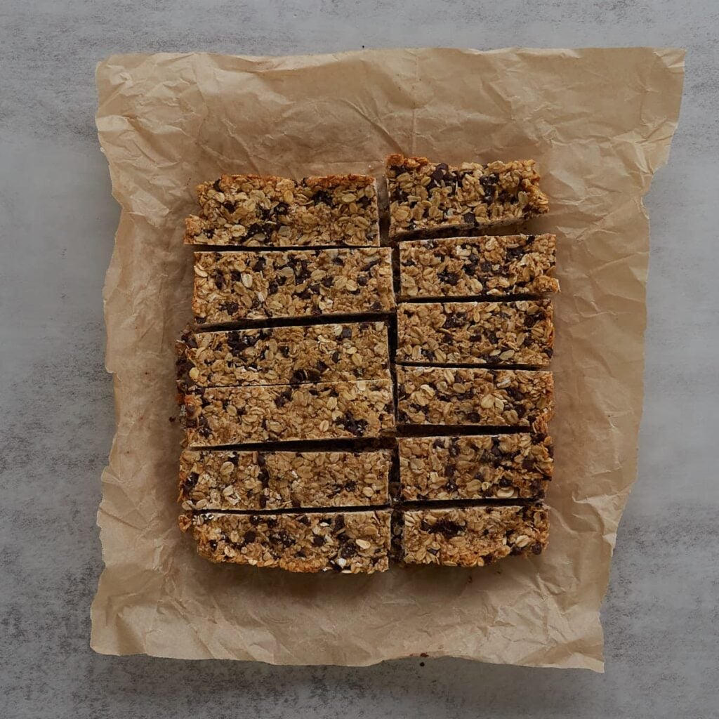 Sourdough granola bars on brown parchment paper cut into 12 rectangles.