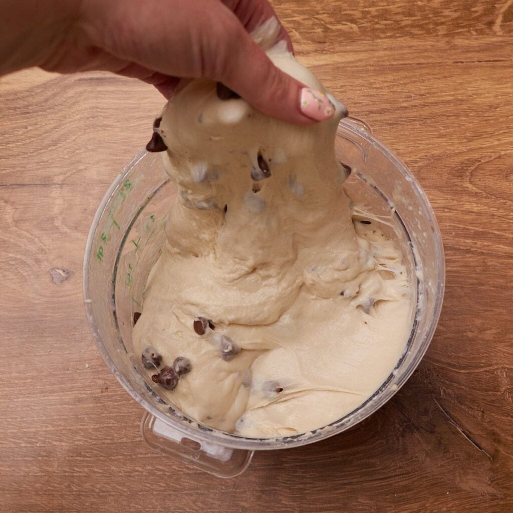 Hand pulling up dough to do a set of stretch and folds.