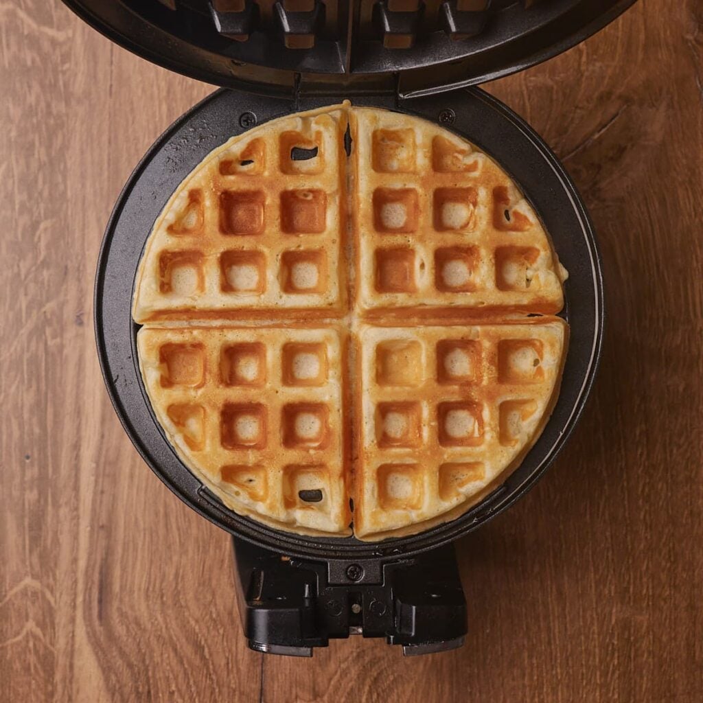 One sourdough waffles freshly cooked in a waffle iron.