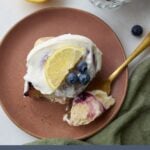 One Lemon Blueberry Sourdough Roll on a brown plate with a gold fork next to it.