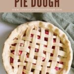 Sourdough pie dough in a lattice top next to a green cloth napkin and with strawberry rhubarb filling.