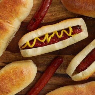 Hot dog buns with hot dogs inside with mustard and ketchup on top.