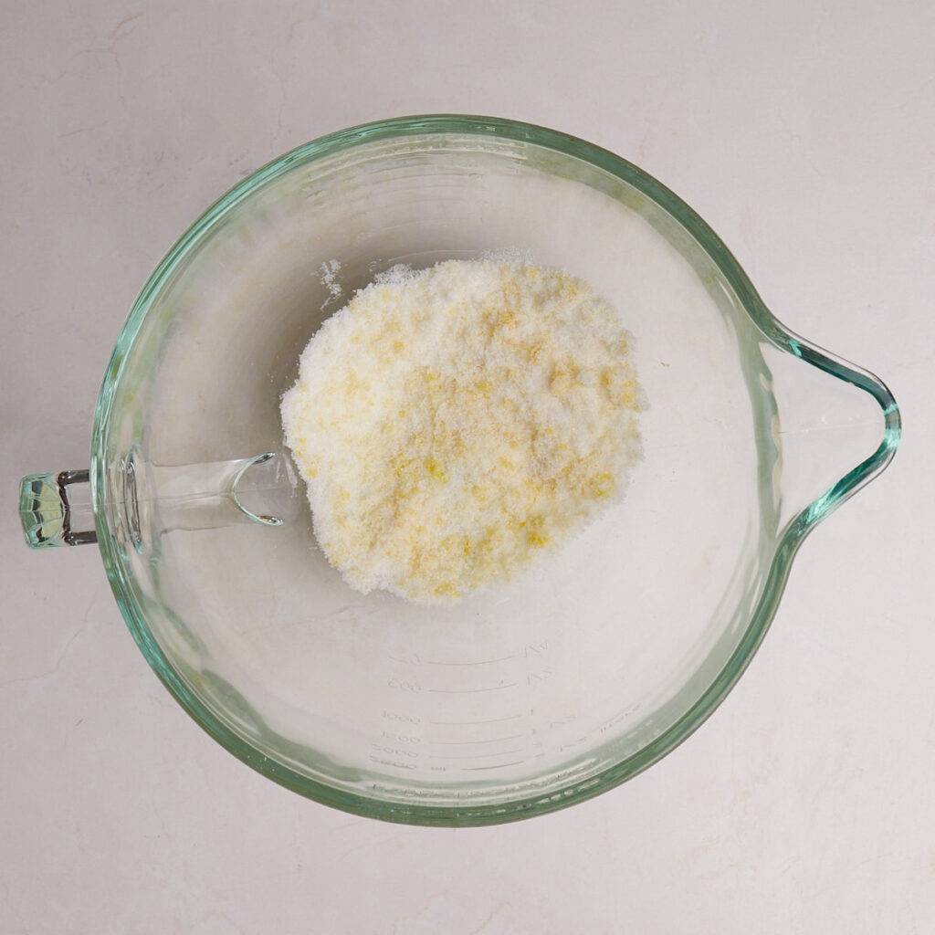 Lemon zest and sugar in a clear bowl for Lemon Blueberry Sourdough Rolls.