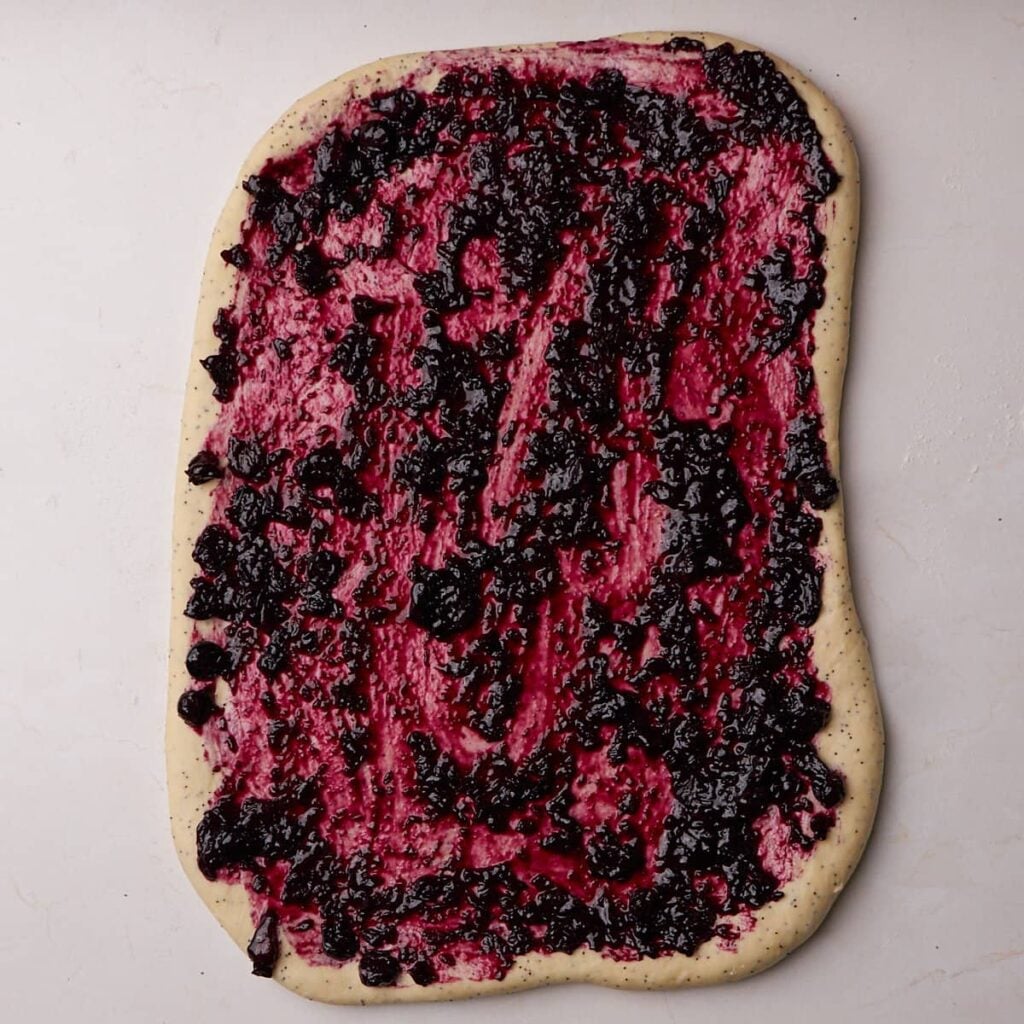 Blueberry filling spread over the dough shaped in a rectangle for Lemon Blueberry Sourdough Rolls.