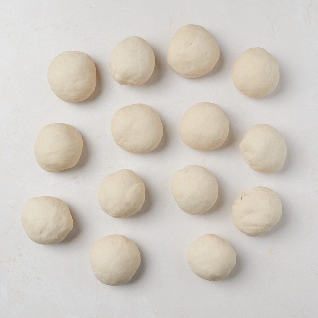 Dough balls for sourdough discard bagels shaped on a white surface.