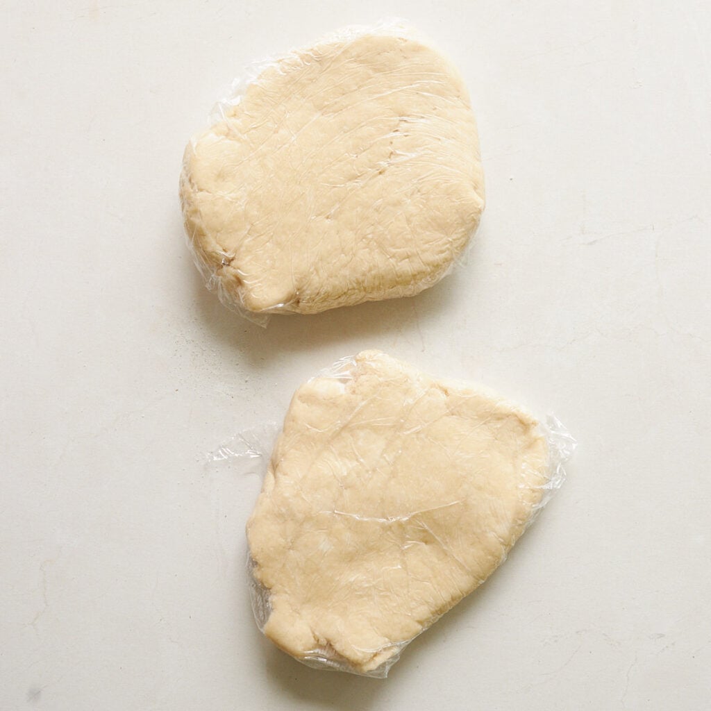 Sourdough pie dough divided into 2 disks and covered in plastic wrap.