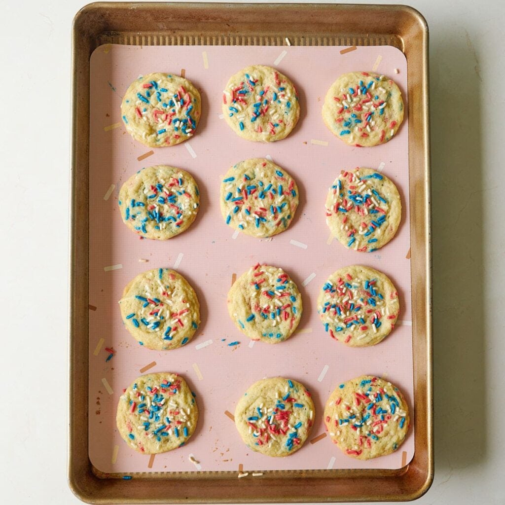 Freshly baked Sourdough Sprinkle Cookies on a lined sheet pan.