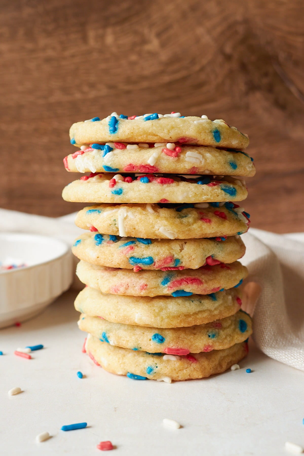 Sourdough Sprinkle Cookies stacked on top of each other next to a white cloth napkin.